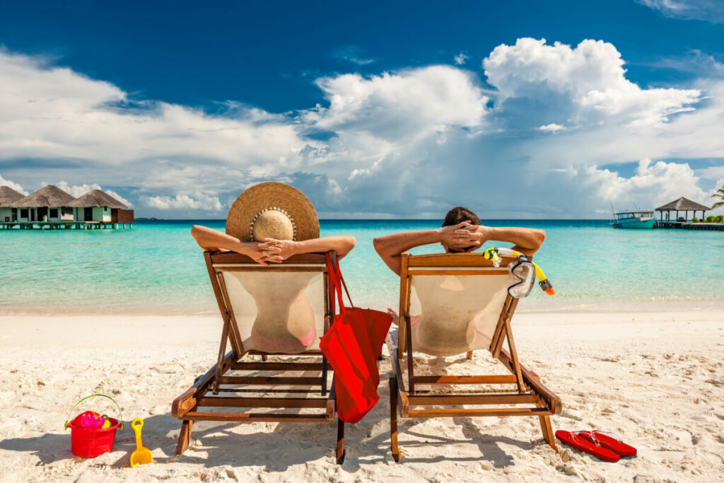 Couple,In,Loungers,On,A,Tropical,Beach,At,Maldives