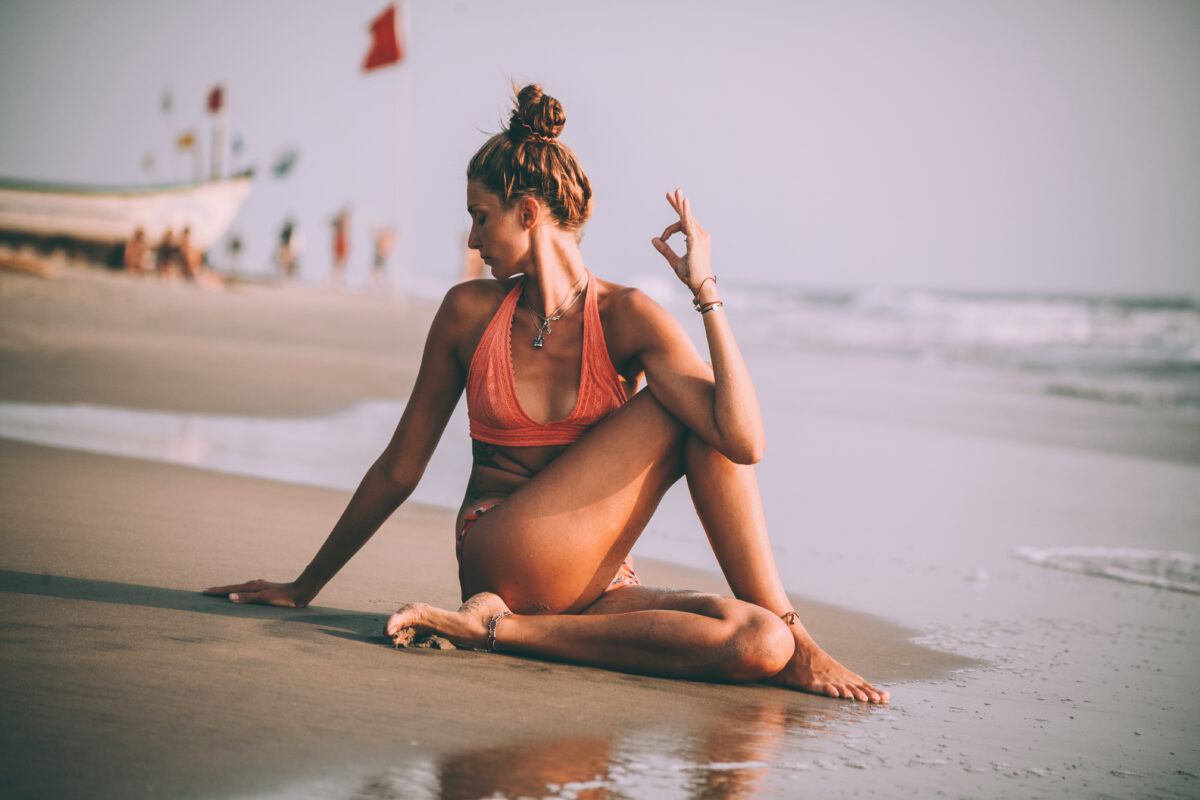 Young,Woman,In,Swimsuit,Practicing,Yoga,On,Beach,At,Goa